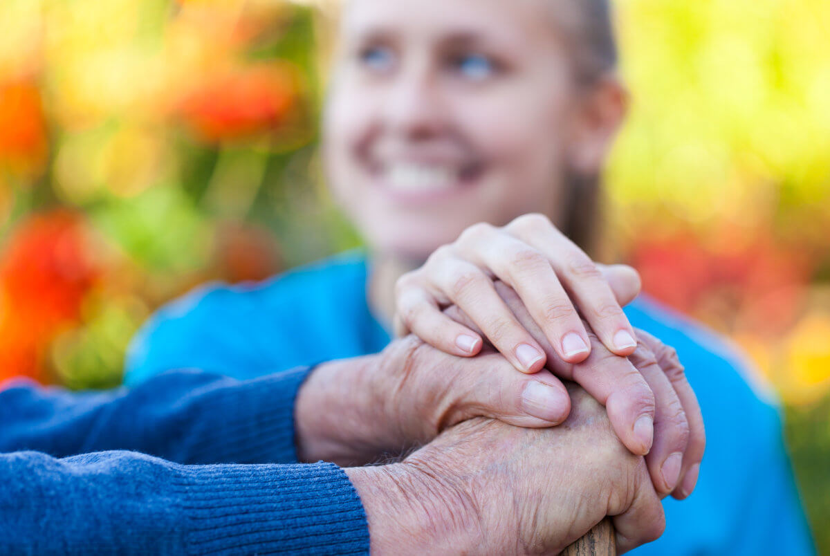 carer holding disabled mans hand