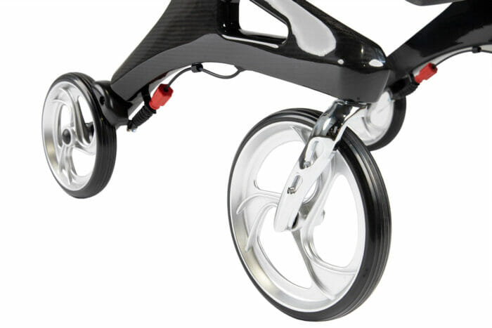 Close-up of the large front castors and carbon fibre frame of a Hero Medical Outdoor Lite Walker with silver multi-spoke wheels