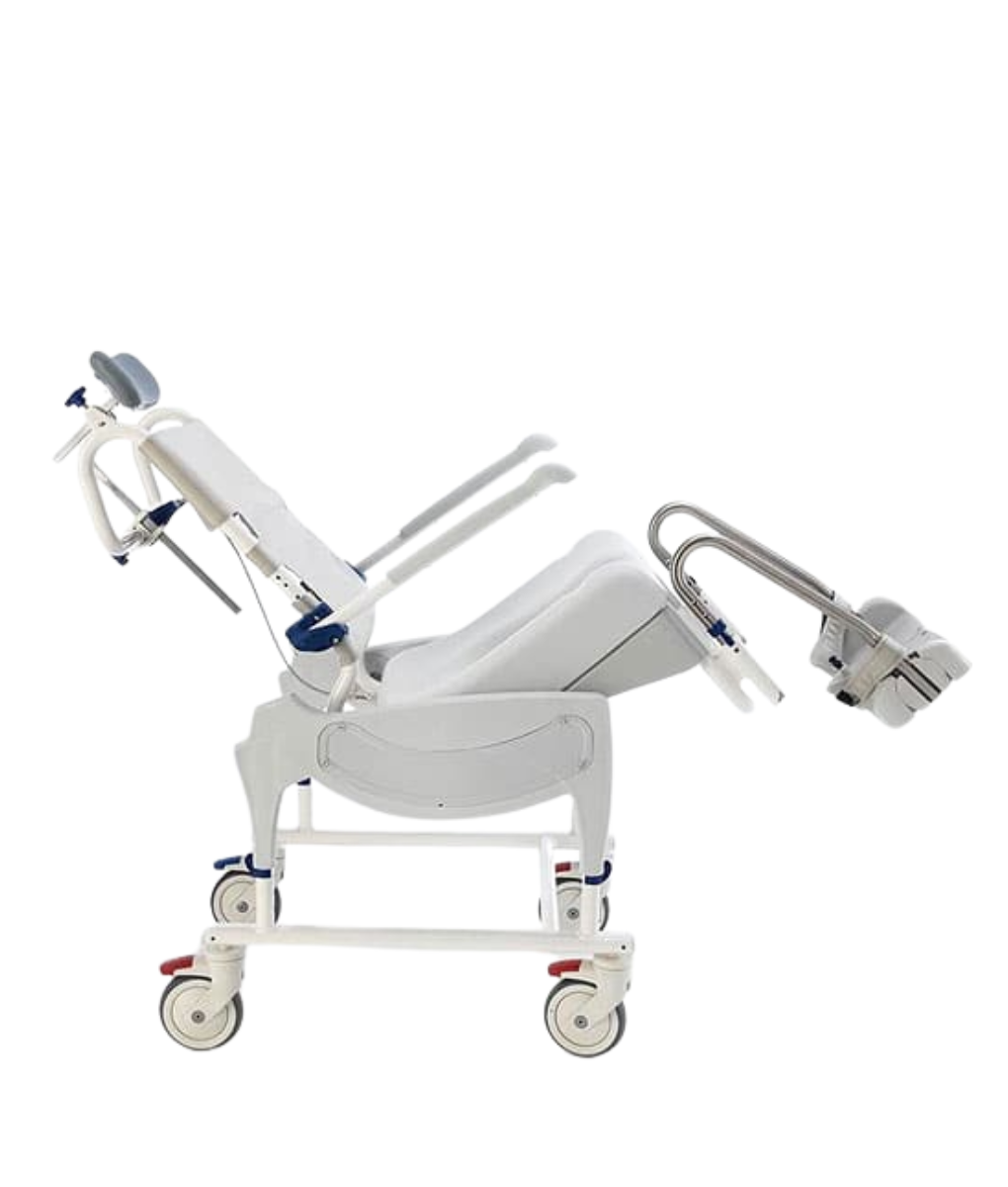 A white Aquatec Ocean Ergo VIP Transit shower commode chair with a light gray contoured seat, padded backrest, and headrest. The chair features swing-away armrests, height-adjustable footrests, and four locking swivel casters for easy transport.