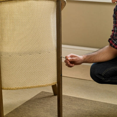 Person assembling or tightening a screw on a wicker chair